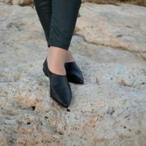 Μπροστινή όψη μαύρων δερμάτινων σανδαλιών φορεμένα επάνω σε πέτρινη επιφάνεια.